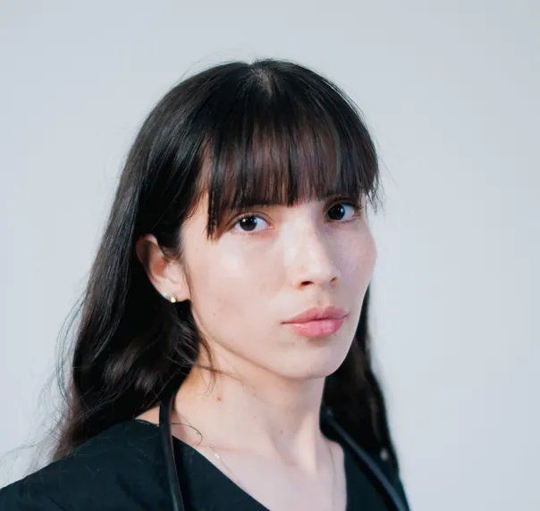 A doctor with a dark fringe in black scrubs, a stethoscope round her neck