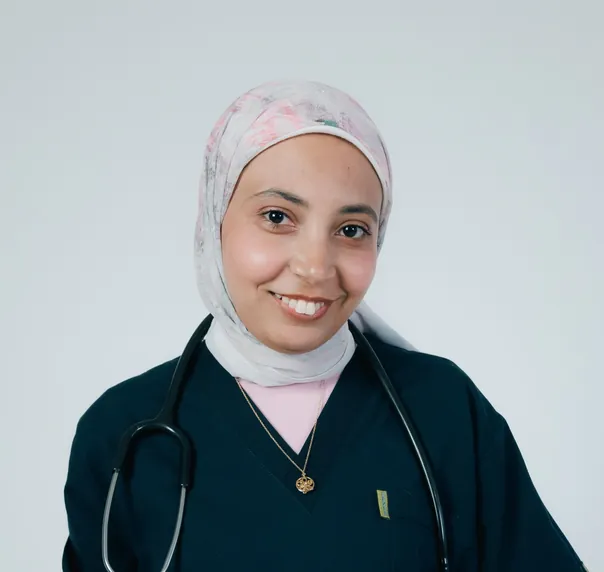 A smiling doctor in a patterned headscarf and dark green scrubs, a stethoscope round her neck