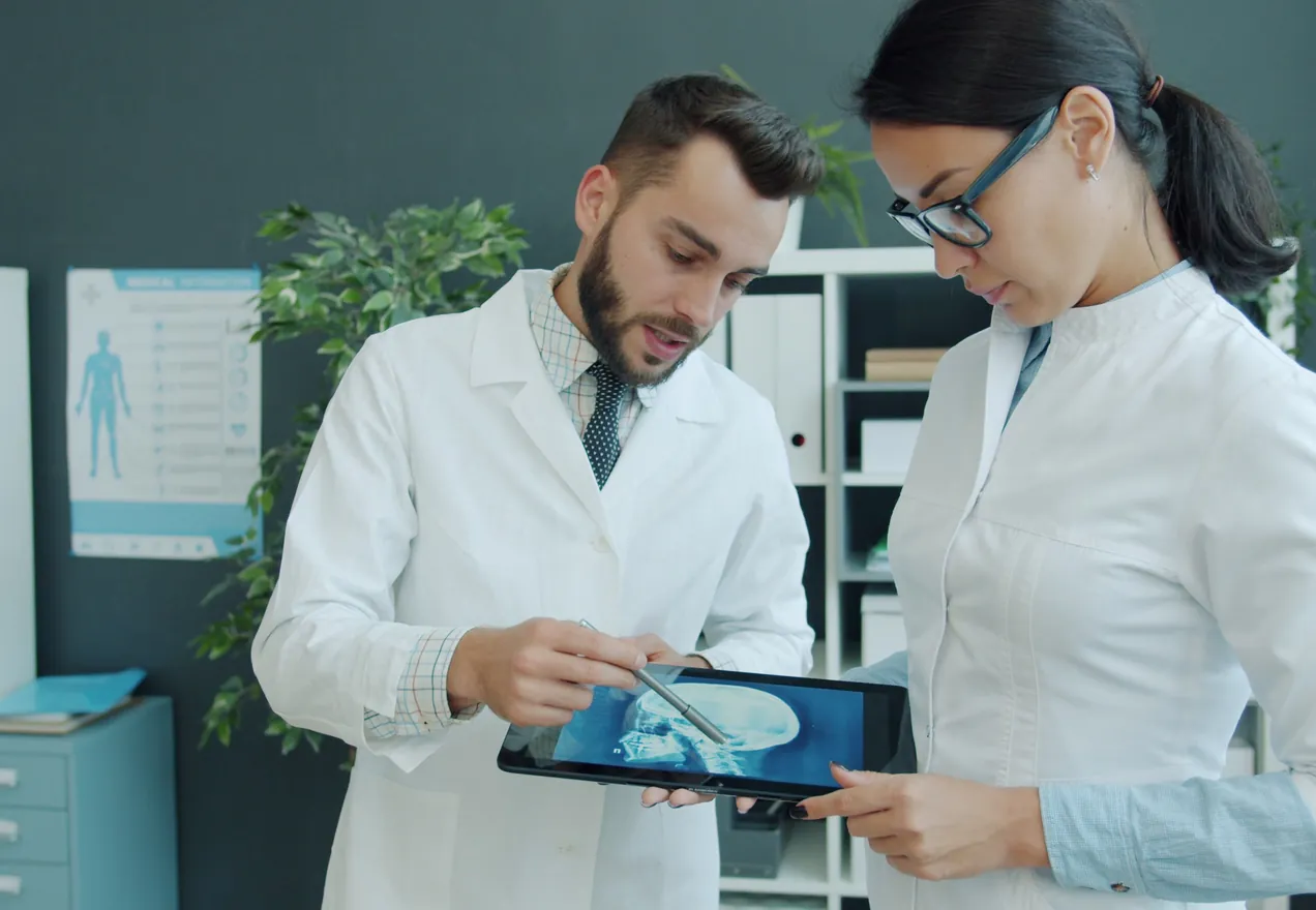 Two doctors in white coats looking at a scan together on a tablet